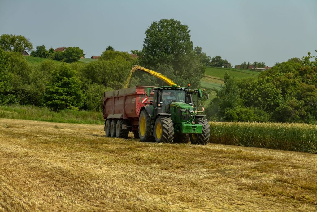 Green tractor harvesting crops in a farm field