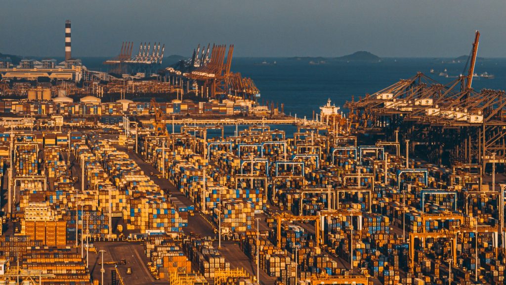 Aerial view of a port with stacked shipping containers and cranes